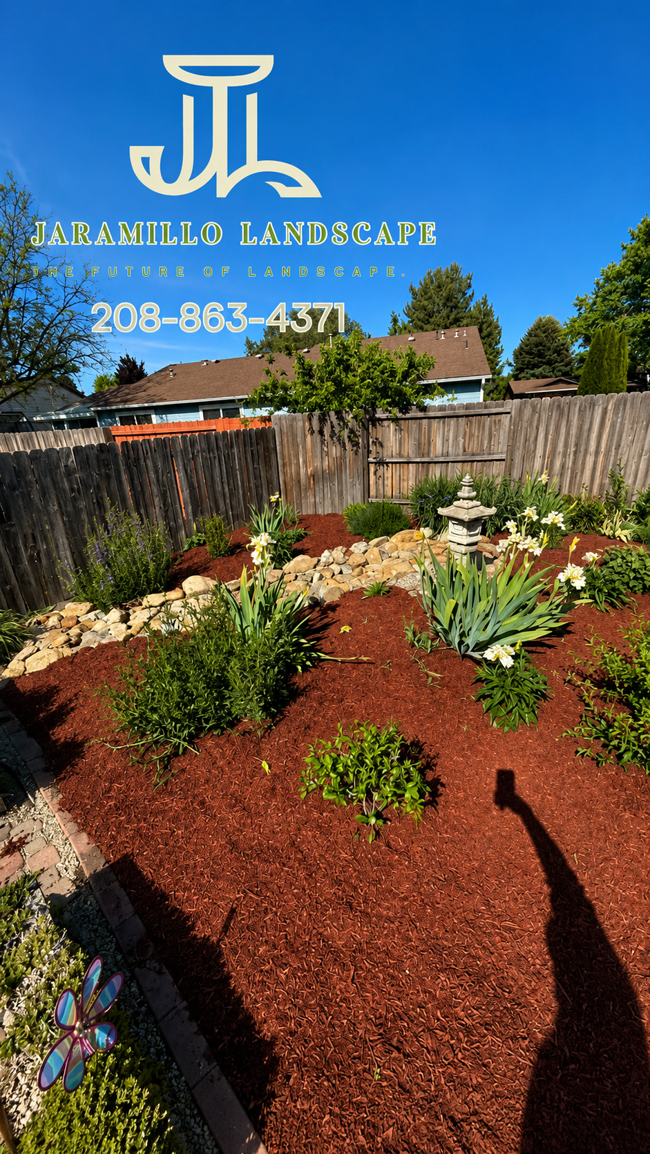 Garden design with red mulch, flowering plants, and stone borders